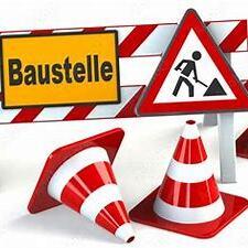 Baustellenschild mit Warnzeichen und roten, wei&szlig;en Absperrungen sowie Verkehrsh&uuml;tchen auf einem wei&szlig;en Hintergrund.