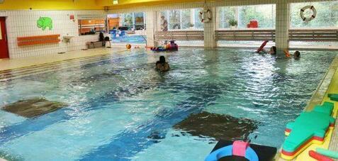 Innenansicht eines Schwimmbeckens mit mehreren Schwimmern, Schwimmspielzeug und bunten Poolelementen.
